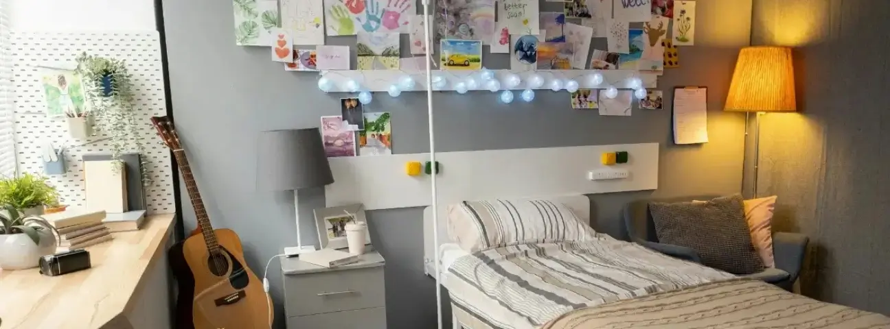 A Personalised Student Bedroom in London With Study Desk Shelving and Guitar.webp
